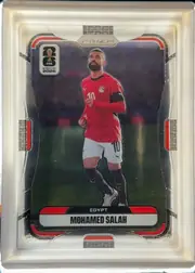 Front of 2026 Panini Prizm FIFA World Cup Soccer MOHAMED SALAH #220 Base, portrait soccer card front featuring Mohamed Salah running in an Egypt red jersey, white shorts, and black socks on a dark stadium background. A…