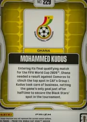 Back of 2026 Panini Prizm FIFA World Cup Soccer Mohammed Kudus #229 Prizm, upright portrait-oriented card back. A gold/yellow patterned field is enclosed by white and gray rounded border elements. Near the top is a white…