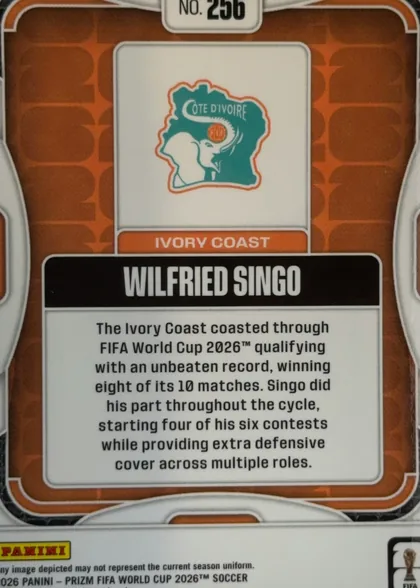 Back of 2026 Panini Prizm FIFA World Cup Soccer Wilfried Singo #256, landscape-oriented card back shown upright. A small white rounded rectangle at the top contains “No. 256”. The orange-brown patterned field has…