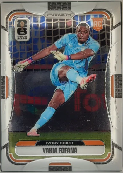 Front of 2026 Panini Prizm FIFA World Cup Soccer Yahia Fofana #255 Base, portrait-oriented soccer card front. A goalkeeper in a light blue Ivory Coast kit is pictured diving in front of a goal net. The PRIZM logo is…