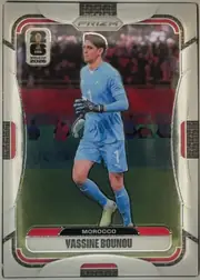 Front of 2026 Panini Prizm FIFA World Cup Soccer Yassine Bounou #296, portrait-oriented soccer card front. A goalkeeper in a light blue Morocco uniform is shown on a field in front of a stadium crowd. The PRIZM logo is…