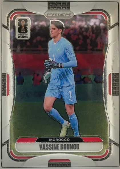 Front of 2026 Panini Prizm FIFA World Cup Soccer Yassine Bounou #296, portrait-oriented soccer card front. A goalkeeper in a light blue Morocco uniform is shown on a field in front of a stadium crowd. The PRIZM logo is…