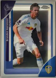 Front of Topps Chrome Brenden Aaronson Base, portrait-format soccer card front. A full-body action photograph of Brenden Aaronson in a white Leeds United kit occupies the center. The left…